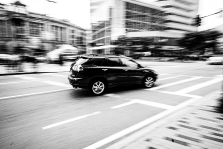 Black and White Picture of Vehicle Driving around Corner with Blurred Background