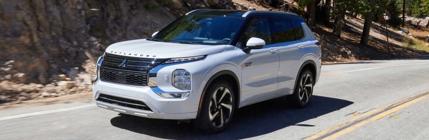 White 2024 Mitsubishi Outlander Plug-In Hybrid SUV Driving on Road